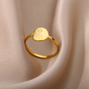 Macro detail of 18K gold stainless steel ring with sun and hands engraving on silk
