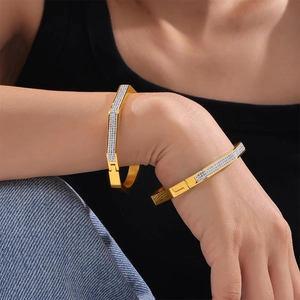 Elegant gold octagon bangle with white pavé zircons worn by a model on dark background