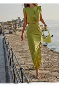Detail shot of the grass green woven handbag paired with a cut-out maxi dress