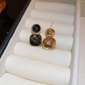Macro view of vintage gold geometric stud earrings with faceted black crystals