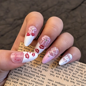 Detail of almond press-on nails with red lip prints, pink bows and small pearls