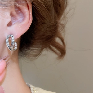 Detail of silver S925 earrings with sparkling zircon crystals in a double C-loop design