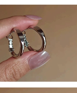 Close-up of minimalist silver hoop earrings with polished mirror finish held in hand