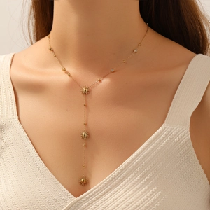 Elegant gold sunflower Y-necklace with tassel pendant worn by a model in warm light