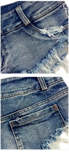 Detailaufnahme der Denim-Textur, orangefarbene Nähte und Fransen an Denim-Shorts