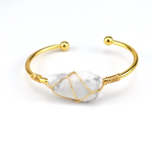 Detail of wire-wrapped natural white stone on a golden bohemian open cuff bracelet