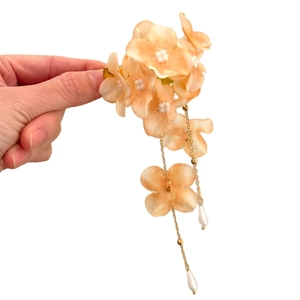 Sweet floral hair clip with pearl tassels and fabric flowers in a handheld view.