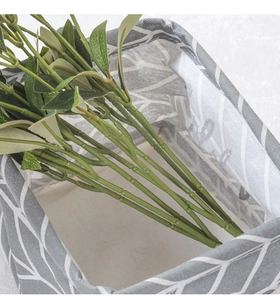 Detail of grey fabric storage basket with white leaf pattern and textile lining texture