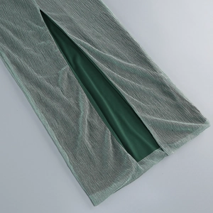 Détail du tissu plissé vert foncé avec reflet métallique et fente latérale haute