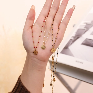 Detailed close-up of golden necklaces with daisy flower pendants and colorful seed beads