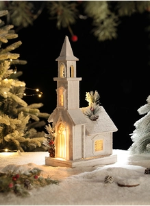 Close-up of a white wooden Christmas church ornament with warm internal LED lights