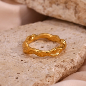Detail of 18K gold plated irregular wavy ring on natural stone with silk background