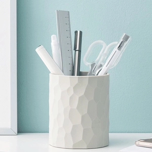 Close-up of a cream-colored silicone face brush with unique 3D geometric honeycomb texture