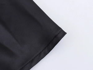 Close-up detail of high-quality stitching and satin fabric texture on black V-neck mini dress