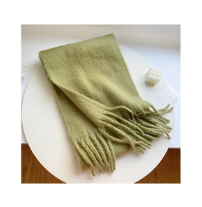 Detail view of grass green plush winter scarf with long tassels and soft brushed texture