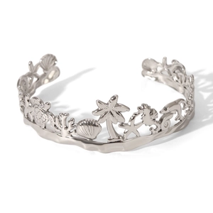 Detail of silver open bangle featuring hollowed-out sea turtles, palm trees and starfish