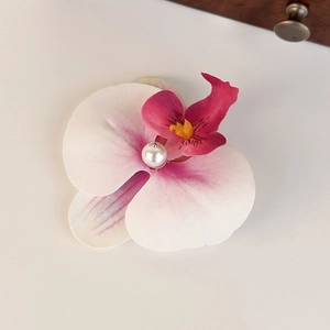 Detail of fabric orchid hair claw with pink gradient petals and a pearl center accent
