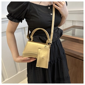 Sac à main trapèze doré avec poignée nouée et porte-monnaie assorti sur robe noire