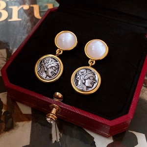 Close-up of vintage portrait earrings with white gemstones in a red velvet jewelry box