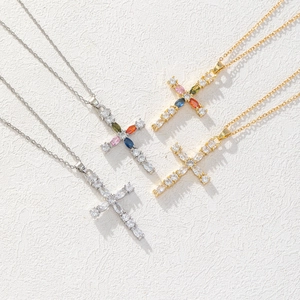 Flat lay of gold and silver cross necklaces with colorful gems and zircon stones