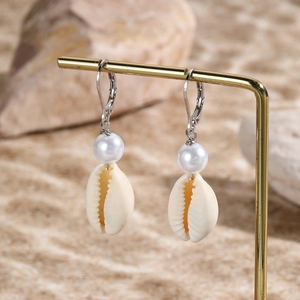 Macro view of ocean style shell earrings with artificial pearl and metal hooks