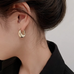 Detailed close-up of a minimalist gold water-drop earring on a model ear