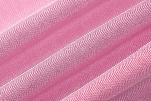 Macro shot of bright pink silk-like fabric with fine knit texture and elegant draping