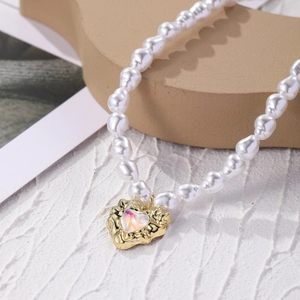 Macro detail of multi-layer baroque pearl necklace with a golden heart-shaped opal pendant
