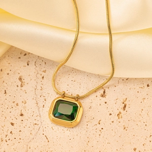 Golden snake chain necklace with emerald green rectangular zircon pendant on silk background