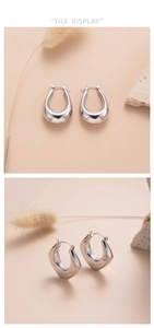 Close-up of silver teardrop hoop earrings showing glossy finish and hollow U-shaped design