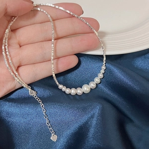 Detail of silver pearl necklace featuring gradient pearls and a heart pendant clasp