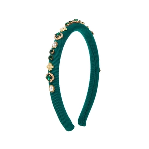 Détail d'un serre-tête tricoté vert avec gemmes d'émeraude, perles et trèfle doré