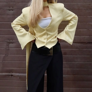 Detailed close-up of light yellow blazer with flared cuffs and V-neckline style