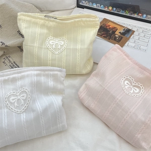 Detailed knit cosmetic bags in white, yellow, and pink with lace heart and bow accents