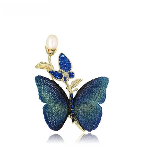 Elegant gold butterfly brooch with blue rhinestones and a white pearl on white background