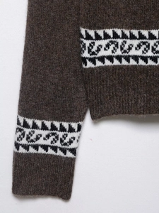 Detailed close-up of dark brown knit sweater with classic Fair Isle geometric pattern
