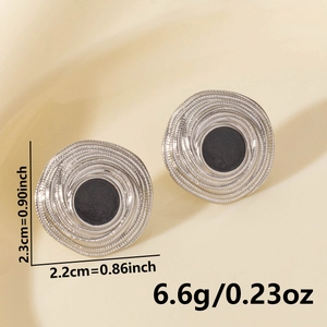 Macro detail of silver geometric spiral earrings with black enamel center and size markings