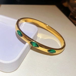 Detailed macro view of marquise green zircons on a polished gold-plated bangle