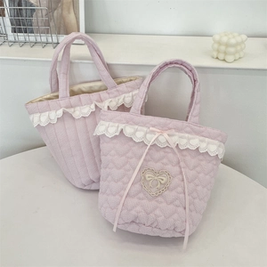 Detailed close-up of quilted heart lace trim and bow on the pink striped handbag