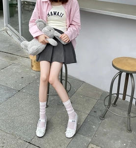 Detail of white striped calf socks worn with ballet flats and pleated skirt