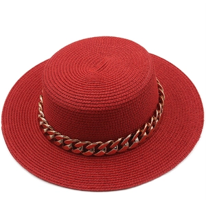 Detail of red boater straw hat with stylish gold metal chain decoration and wide flat brim