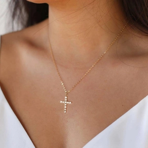 Close-up of gold plated cross necklace with micro-pave cubic zirconia on a model