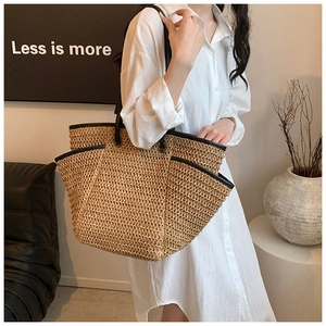 Detail of a large straw tote bag with black leather straps for beach holidays