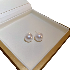 Élégantes boucles d'oreilles perles blanches dans un écrin à bijoux doré de luxe