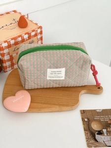 Detail of pink and green checkered quilted makeup bag with zipper and logo patch