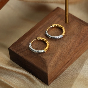 Two-tone hammered texture gold and silver hoop earrings on elegant silk background