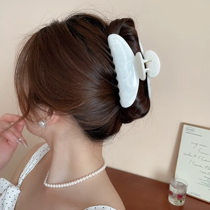 Détail d'une pince à cheveux en acrylique marbre blanc portée par un mannequin élégant