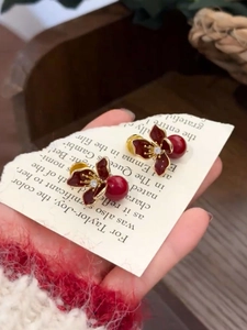 Détail macro de boucles d'oreilles fleurs bordeaux avec perles et bordure dorée femme
