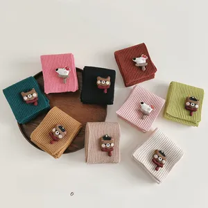 Macro shot of colorful knitted kids' neck warmers with cute cartoon animal patches