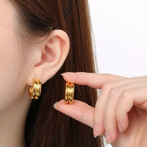 Macro shot of gold C-shaped triple hoop earrings showing size and glossy metal texture